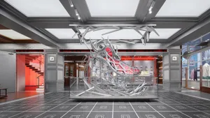 A modern shoe store with a large metal shoe sculpture as the centerpiece, surrounded by a glass display case and sleek interior design