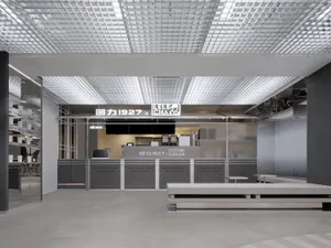 A modern restaurant interior with a large dining area featuring multiple benches and a counter, well-lit for a welcoming atmosphere