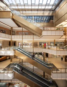 A large commercial building with a modern design, featuring a central metal spiral staircase, large glass windows, and bright lighting