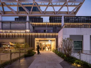 A dimly lit modern lobby with a large glass wall, metal frame, and concrete building material