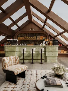 A dimly lit modern bar area with a wooden bar, marble countertop, and decorative items
