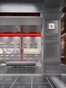 A modern shoe store with a red accent wall, showcasing a variety of shoes on display, and a bench for customers to sit and relax