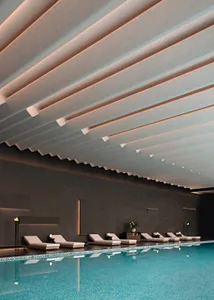 A spacious pool area with lounge chairs and a large white ceiling, surrounded by a luxurious and relaxing environment