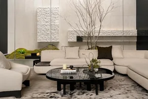 A modern living room with a black coffee table, couch, and chair, decorated with potted plants and featuring clean lines and minimalistic decor