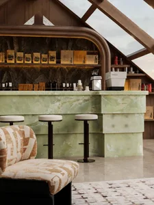 Cozy modern bar area with a marble counter, white stools, and soft lighting