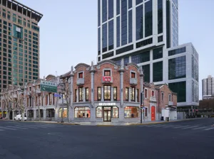 一座大型華麗建築，擁有醒目的紅磚外觀、鐘塔和拱形入口，位於城市環境中，搭配柔和且擴散的光線