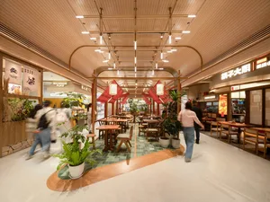 A bustling modern restaurant with dining tables, chairs, and potted plants, featuring a lively and inviting atmosphere