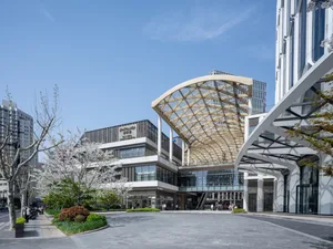 A large commercial building with a glass roof, featuring a modern architectural style and a spacious interior with natural light and people walking around