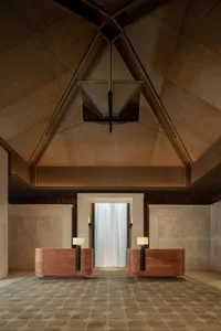 A modern lobby with wooden benches and a stone ceiling, featuring a light fixture and a clean, minimalist design