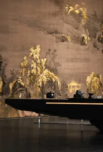 A luxurious dining space with a black table, gold wall, and a large painting, surrounded by vases and exuding an elegant atmosphere