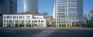 A city street lined with tall glass and steel buildings, surrounded by trees, creating a calm and peaceful atmosphere