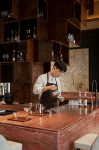 A warm and inviting kitchen with a man preparing a drink, surrounded by wood countertops and various kitchen appliances