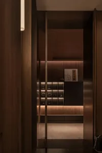 Warm and cozy kitchen dining area with wooden floors and walls, a dining table, and a cupboard, lit by dim lighting