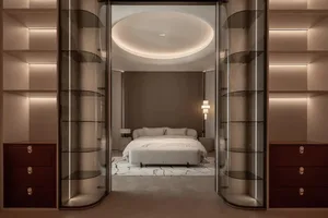 Cozy bedroom with a bed, couch, and chair, featuring a large window, wood, and glass, with soft and warm lighting