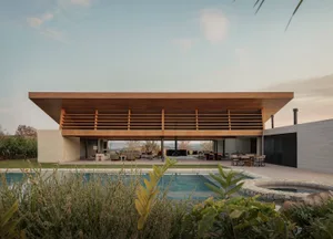 A large, modern house with a pool and wooden exterior, featuring a spacious interior with natural light and comfortable furniture