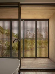 Bathroom with a bathtub and shower, surrounded by concrete walls and natural light from windows
