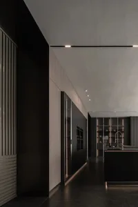 A dimly lit modern kitchen with wooden countertops, a sink, oven, and refrigerator