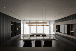 A spacious living room with a long dining table and chairs, a couch, and a hanging light fixture, in a contemporary style
