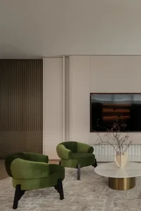Comfortable living space with a flat screen TV, couch, and chair in a well-lit room with white walls and a modern design