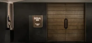 A dimly lit doorway with a traditional sign above it, set in a commercial or public space with a wooden doorway