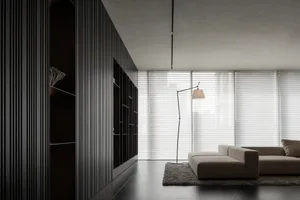 Dimly lit living room with a couch, chair, and lamp, suggesting a modern style with a focus on comfort and functionality