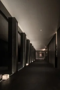 A dark and empty hallway with concrete pillars on either side, creating a sense of quietness and emptiness