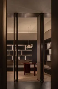 Cozy dining space with a wooden table, a chair, and a hanging light, set against a black wall and wooden floor