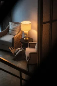 Cozy living room with a vintage aesthetic, featuring a couch, chair, and lamp, set in a dimly lit space
