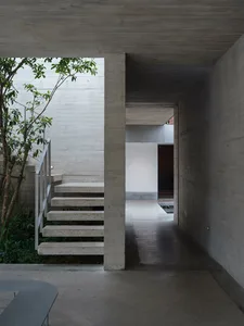 Modern building with concrete and metal materials, natural light, and a staircase leading to a doorway