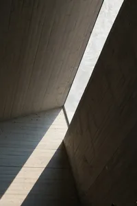 A modern concrete building with a large window on the side, surrounded by natural light and a calm atmosphere