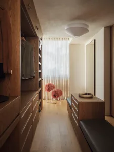 Cozy modern bedroom with a wooden floor, white wall, and dim lighting, featuring a bench and two pink feathered objects