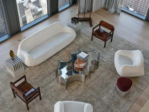 A modern living room with a white couch, a chair, and a coffee table, decorated with a rug and surrounded by various pieces of furniture and books, in a well-lit and inviting atmosphere