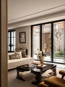A modern living room with a black and white color scheme, white furniture, and a well-lit space with a couch, coffee table, and vase of flowers