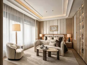 Comfortable living room with a beige couch, a white chair, and a coffee table, well-lit with natural and artificial light
