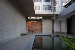 A bright and inviting open space with a large glass wall, a brick wall, and a pool of water, surrounded by a modern building with a focus on natural light