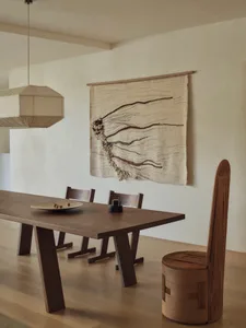Dining room with a wooden floor and table, surrounded by four chairs, and a hanging light fixture, creating a warm and inviting atmosphere