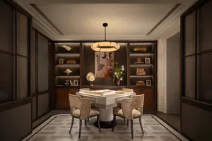 A modern dining room with a dining table and chairs, decorated with books, a clock, and a bowl, and illuminated by a light, creating a warm and inviting atmosphere