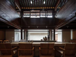 Warm and inviting restaurant with a wooden theme, dim lighting, a bar with a coffee maker, and a dining area with a table and chairs