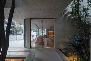 A large, open room with a high ceiling, featuring various seating options, natural light, and warm wood tones