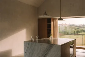 A well-lit kitchen with a marble countertop, sink, window, and door, designed for functionality and aesthetics