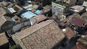 A city courtyard with a mix of old and new brick buildings, a staircase leading to a rooftop, and a charming atmosphere