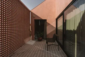 Cozy living room with a brown wall, a red wall, a chair, and a potted plant, well-lit and inviting