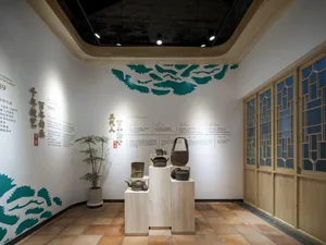 A museum-style room with a pedestal display of vases and baskets on a tile floor, surrounded by a white color scheme and soft diffused lighting