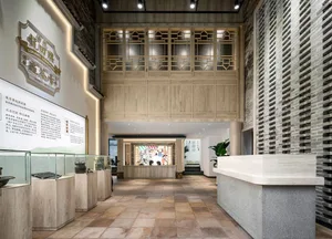 A well-lit room with a wooden floor, marble counter, glass display case, wooden ceiling, and stone wall, showcasing art and artifacts
