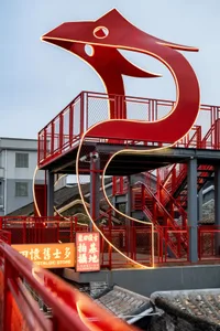 A modern staircase with a red railing and sculpture, set against a red and white background, with natural light and a mix of modern and traditional elements