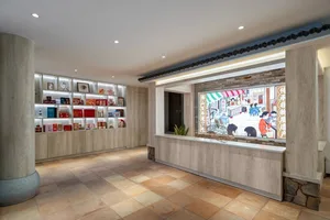 A well-lit bookstore with a wooden counter and a display of books in various positions, set against a bright background with natural light from a large window
