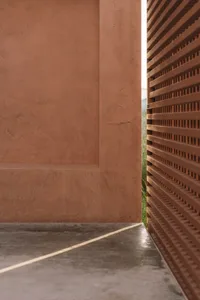 Exterior view of a traditional brick house with a brown wooden door, set in a natural outdoor environment with daytime lighting