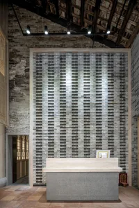 A dimly lit lobby with a wooden countertop featuring a tile design and a brick wall adding a rustic touch