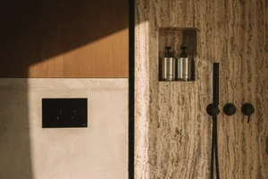 A well-lit bathroom with a wooden door, marble countertop, and white marble wall