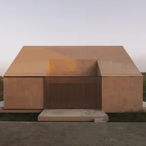 A modern house with a curved roof, concrete exterior, wooden door, and a grassy area, bathed in warm golden light